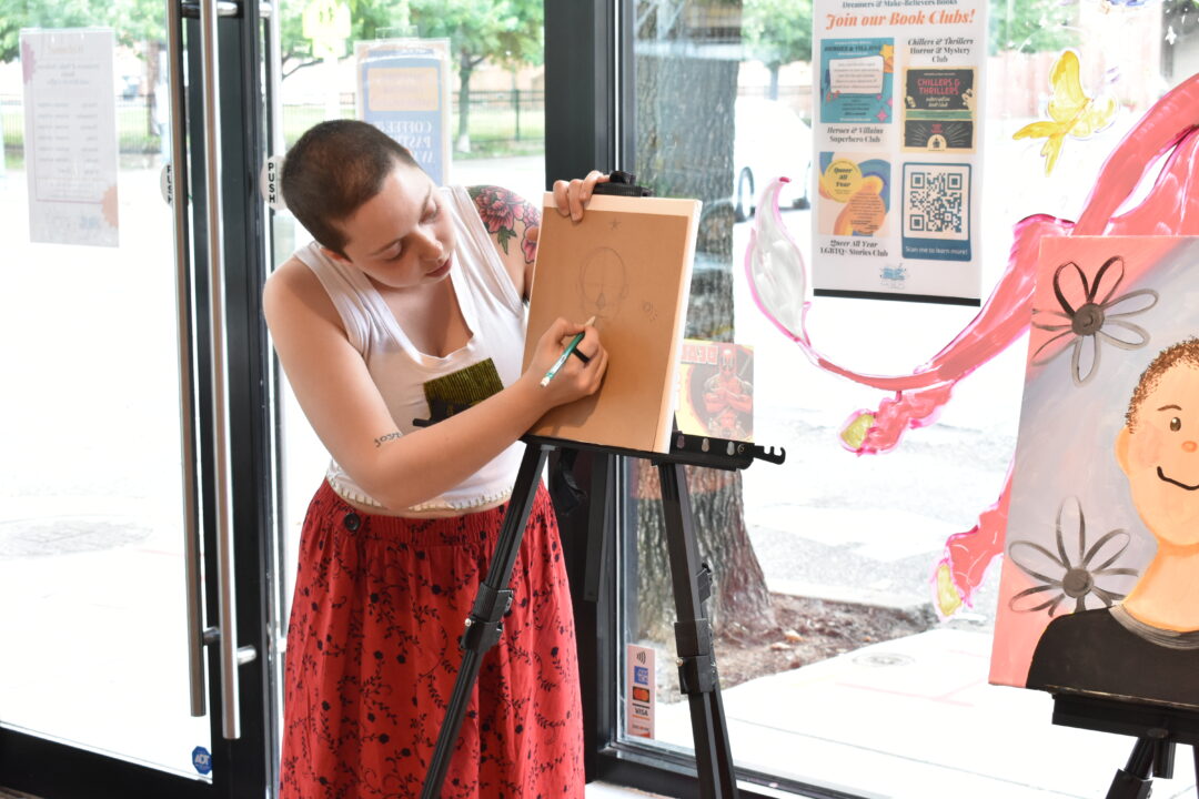 Human drawing on canvas on easel, possibly instructing a class