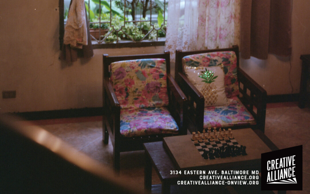 Image of a living room with red drapes and chairs facing a coffee table with a chess set.